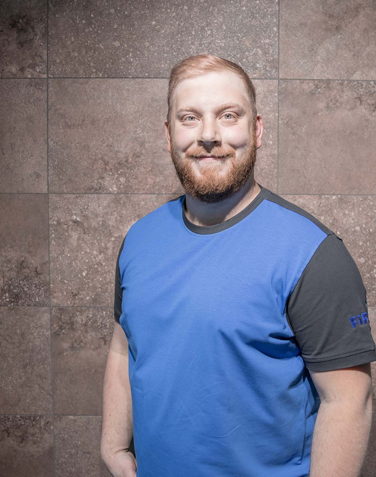 Das Portrait eines Mitarbeiters Rene Haider mit einem blauen T-Shirt