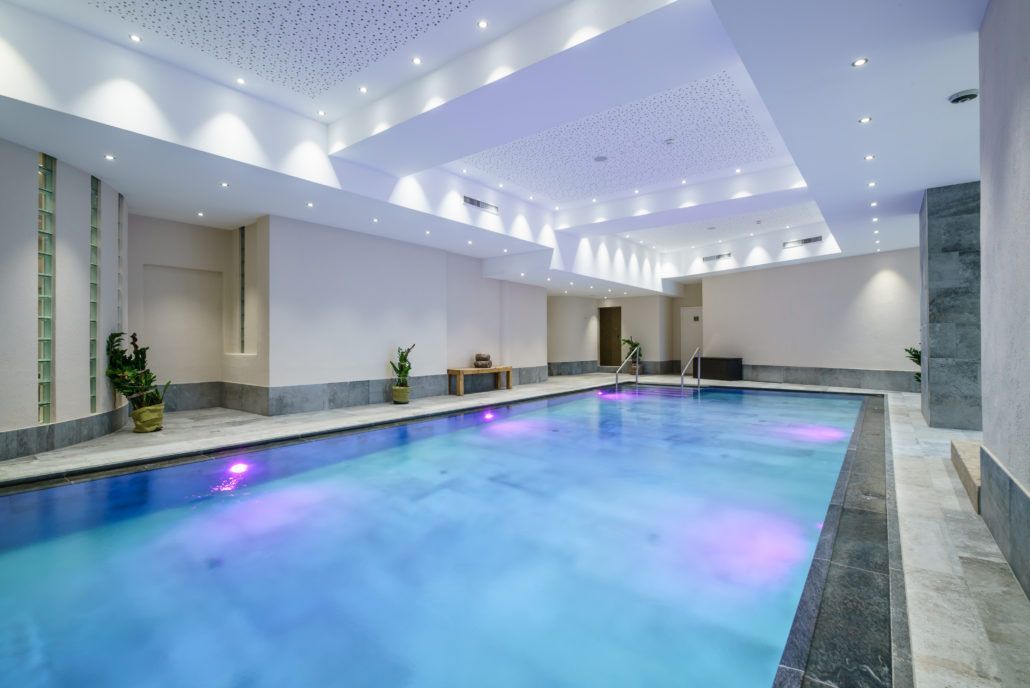Ein großes Hallenbad mit violetten Lichtern an der Decke.