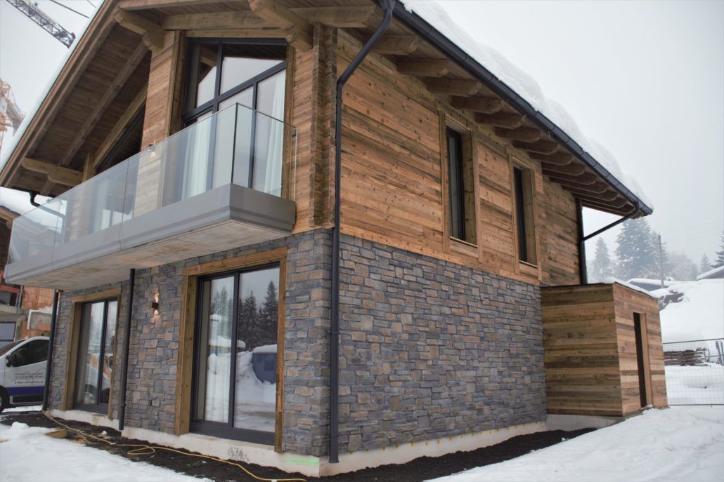 Ein Haus mit vielen Fenstern und einem Balkon ist mit Schnee bedeckt.