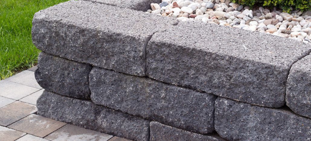 Eine Steinmauer mit einem Blumentopf voller Steine und einer Pflanze darin.