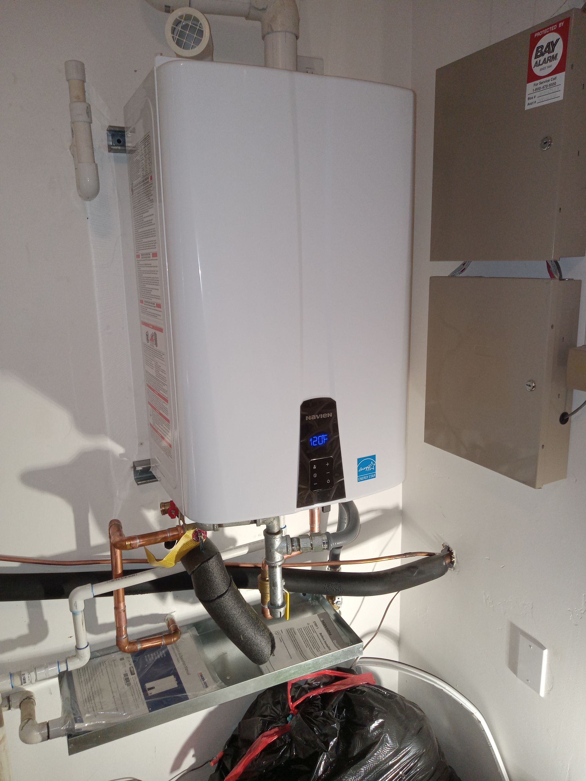 A white boiler is sitting in a room next to a washing machine.