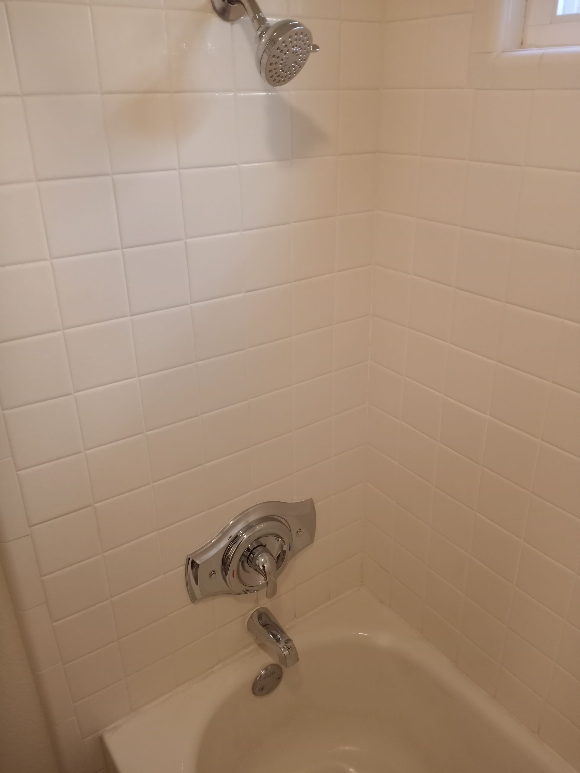 A bathroom with a bathtub and a shower head.
