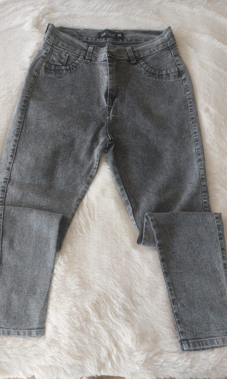 Pantalones vaqueros de mezclilla gris con efecto lavado ácido sobre una superficie blanca y esponjosa.