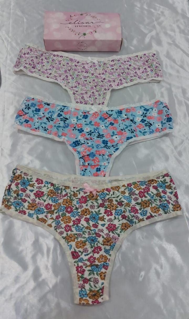 Tres tangas con estampado floral y una cajita sobre una superficie blanca.