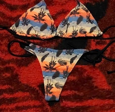 Bikini con estampado tropical en tonos azules, naranjas y blancos, con detalles de lazo negro
