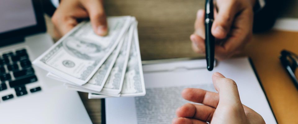 A Man Holding Money and Ballpen — Fishers, IN — Norwood Economics A Man Holding Money and Ballpen — Fishers, IN — Norwood Economics