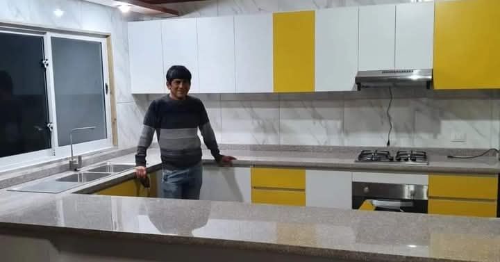 Un hombre está de pie en una cocina con gabinetes amarillos.
