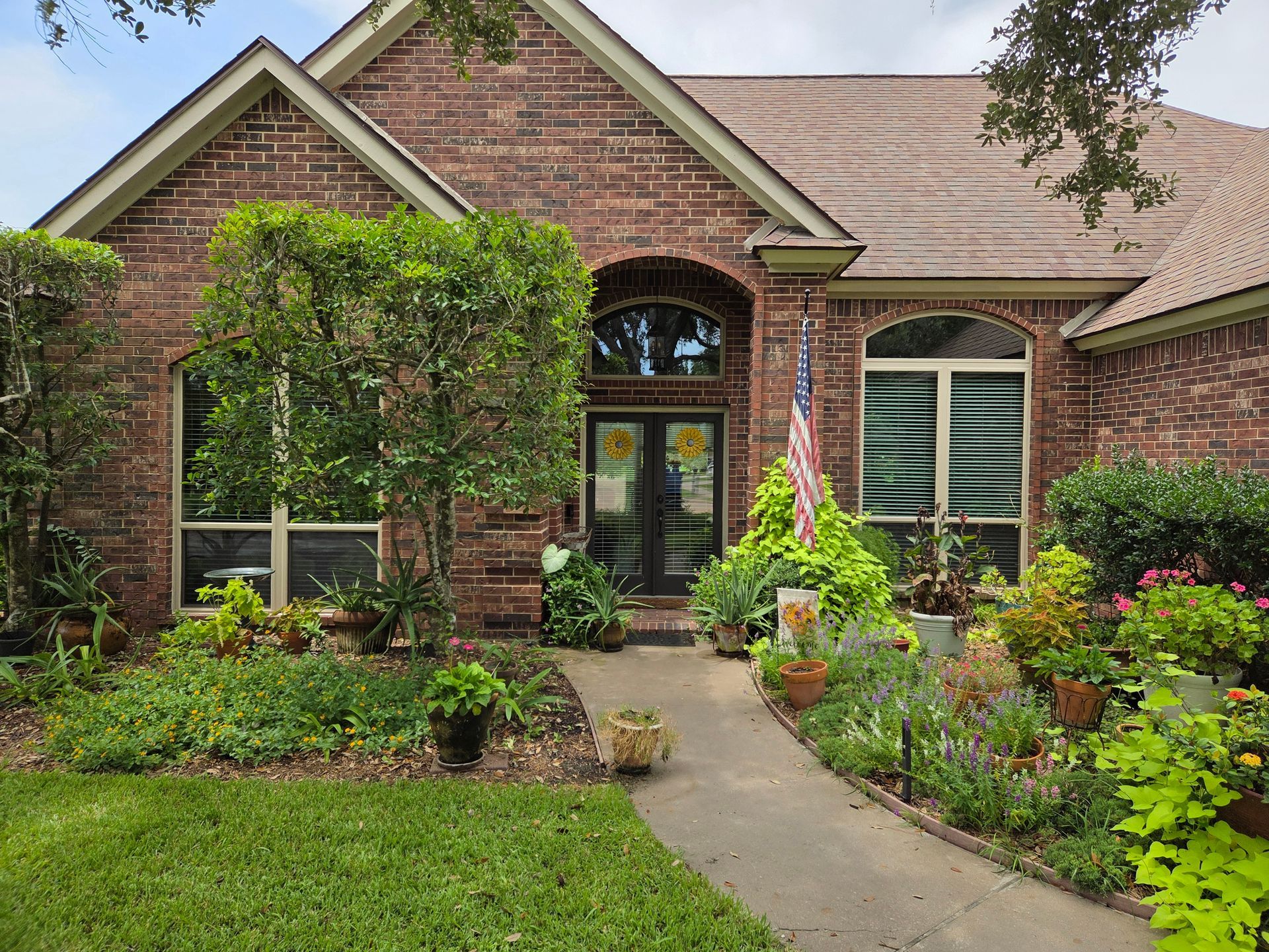 Brick house with garden path leading to double front doors, lush landscaping.