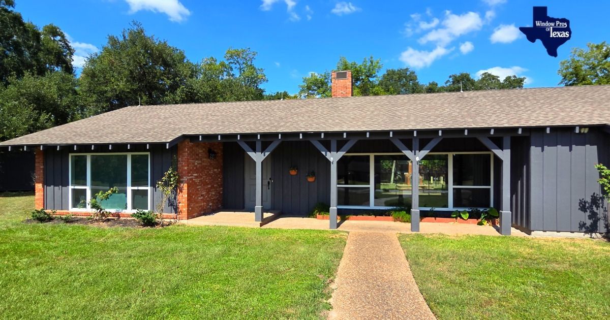 Exterior of a one-story house with a brick facade and dark gray siding. A covered porch and green lawn are visible.