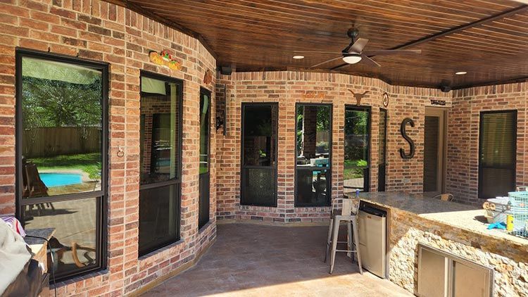 Outdoor patio with brick walls, arched ceiling, windows, and a built-in bar.
