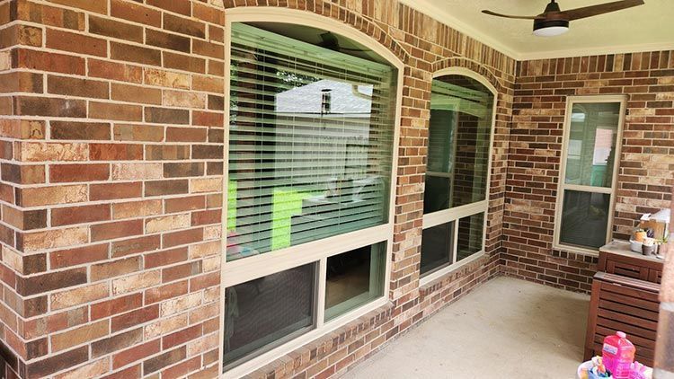 Brick patio with large windows and a ceiling fan.
