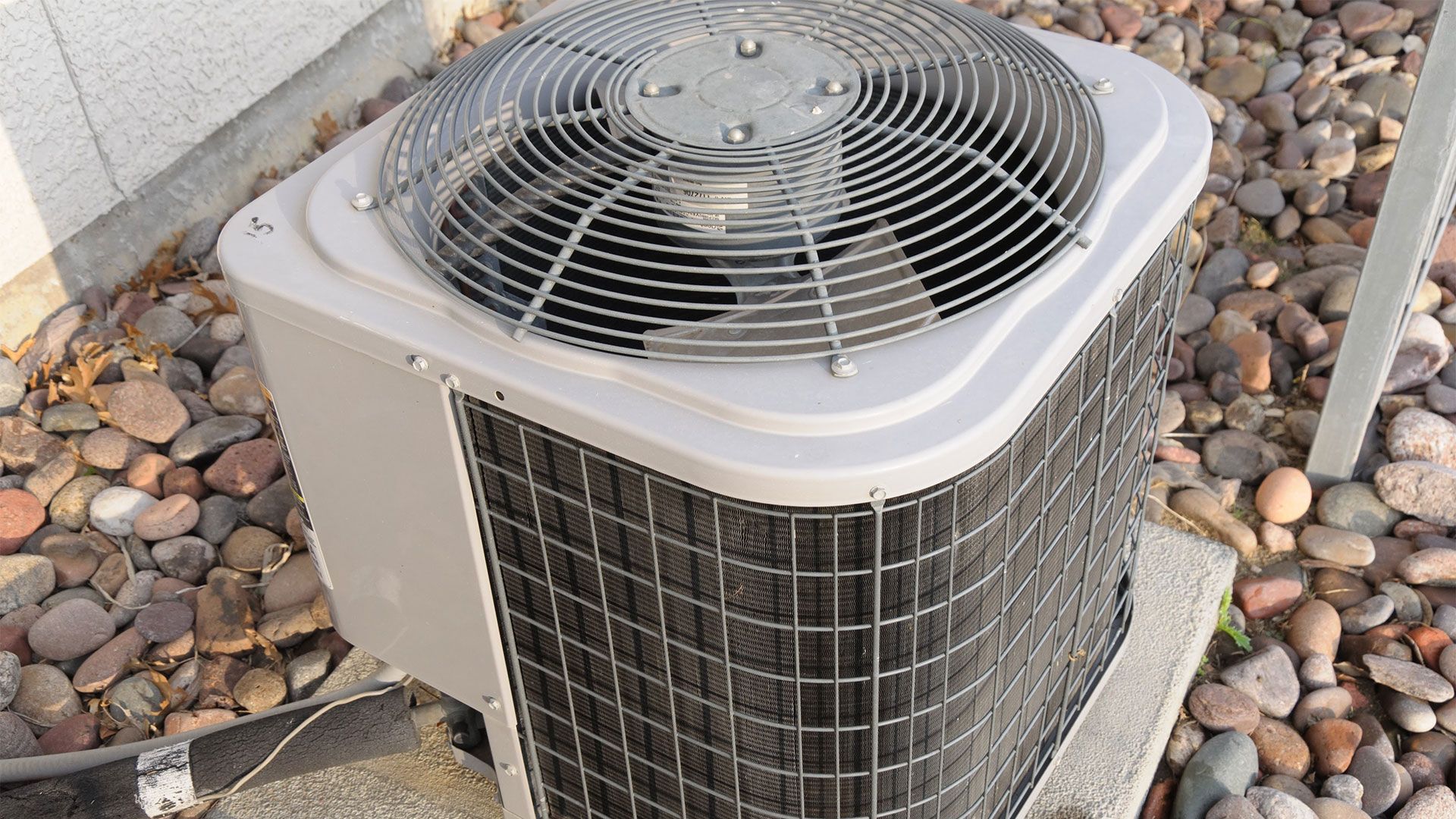 A large air conditioner is sitting on top of a pile of rocks.
