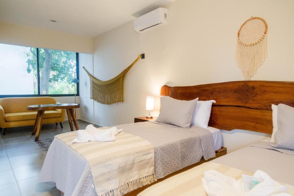 Una habitación de hotel con dos camas, un sofá y una hamaca. Hotel Maculan