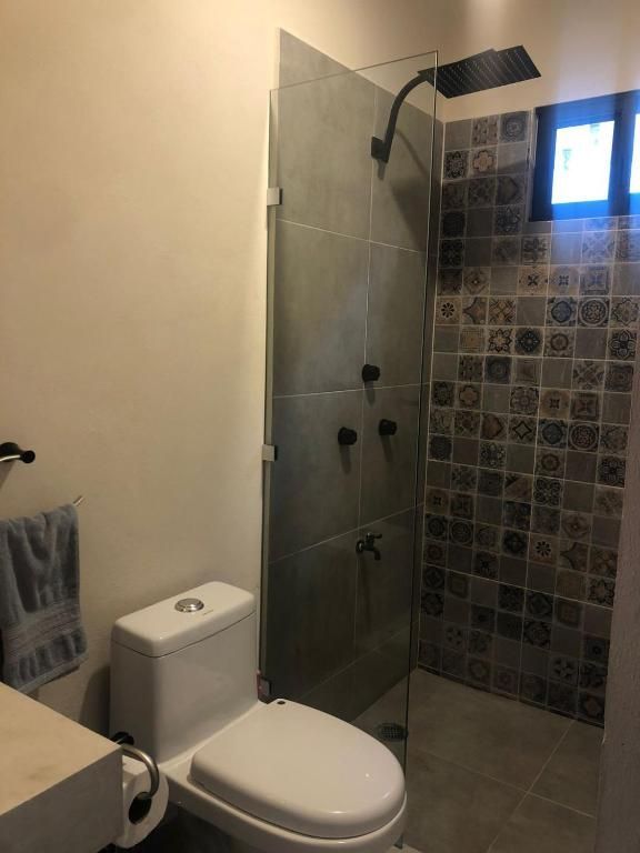 Un baño con inodoro y ducha a ras de suelo.