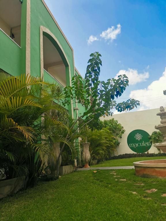 Un edificio verde con una fuente delante.