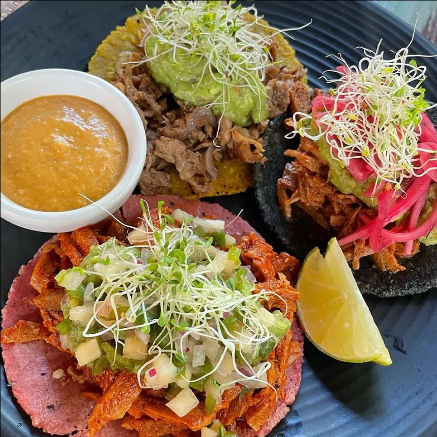 Un plato de comida con un bol de salsa y una rodaja de limón.