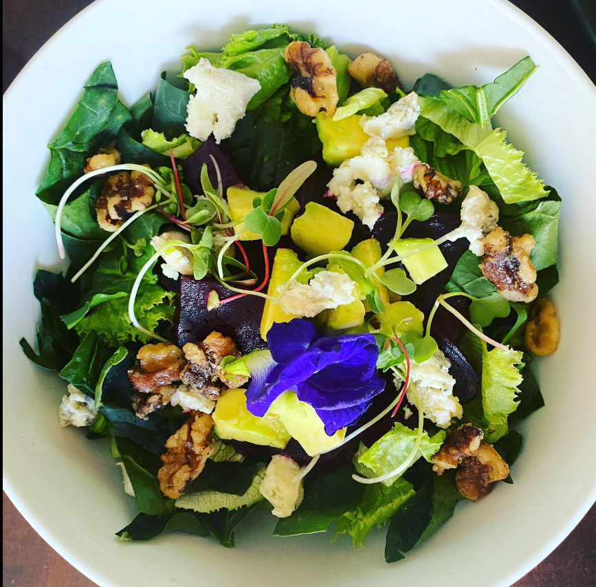 Una ensalada con una flor morada en el medio.