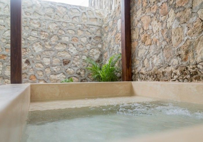 Una bañera de hidromasaje llena de agua frente a un muro de piedra.
