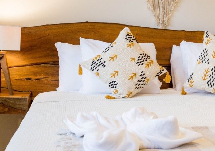 Una cama con sábanas y almohadas blancas y un cabecero de madera.