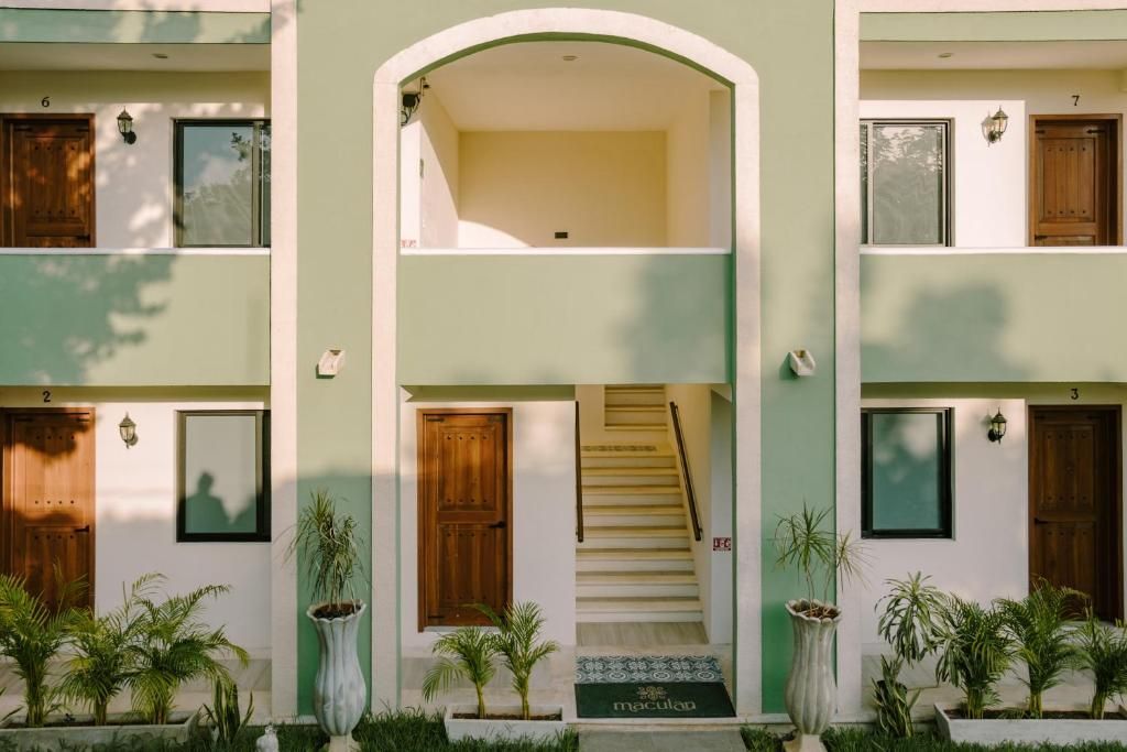 Un edificio de apartamentos verde y blanco con escaleras que conducen al segundo piso.
