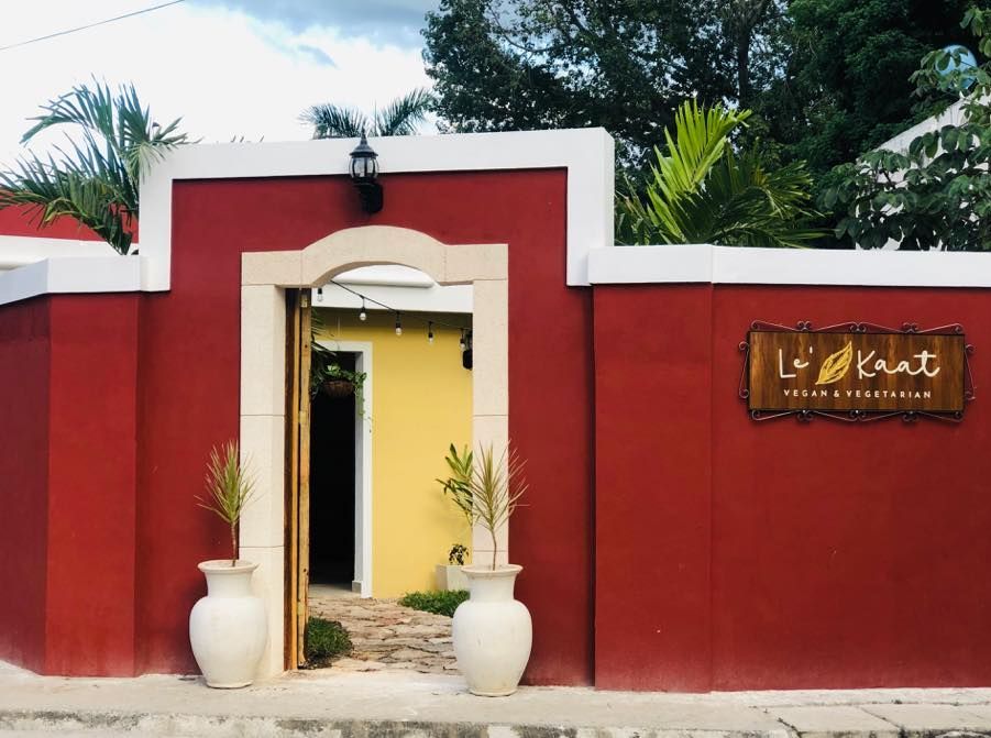 Un edificio rojo y amarillo con un cartel de madera en el costado.
