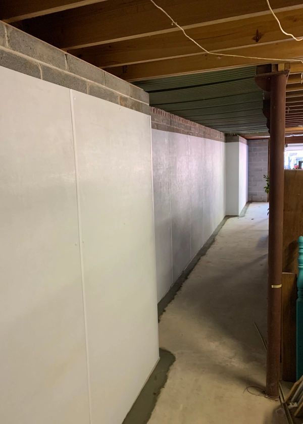 A hallway in a basement with white walls and a concrete floor.