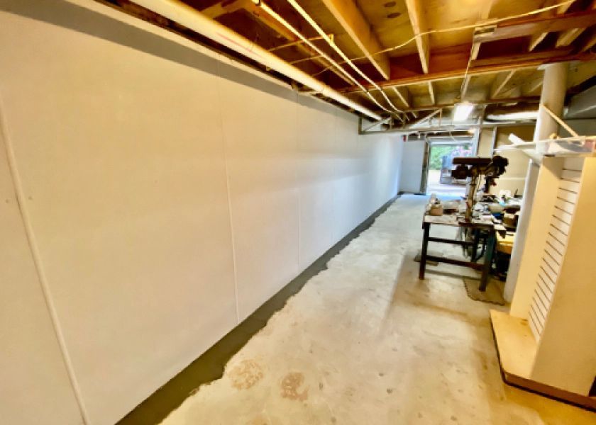 A long hallway in a basement with a table and a drill