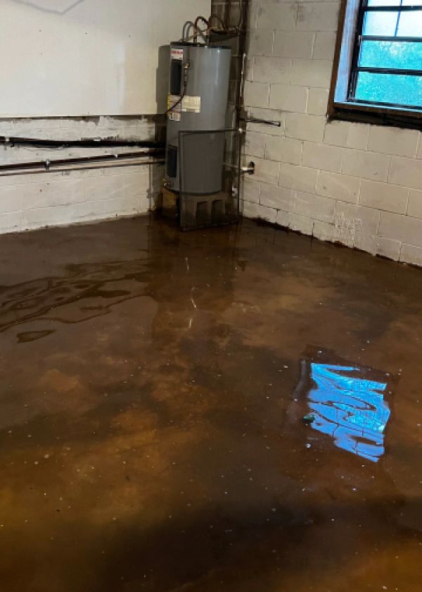 A flooded basement with a water heater and a window.