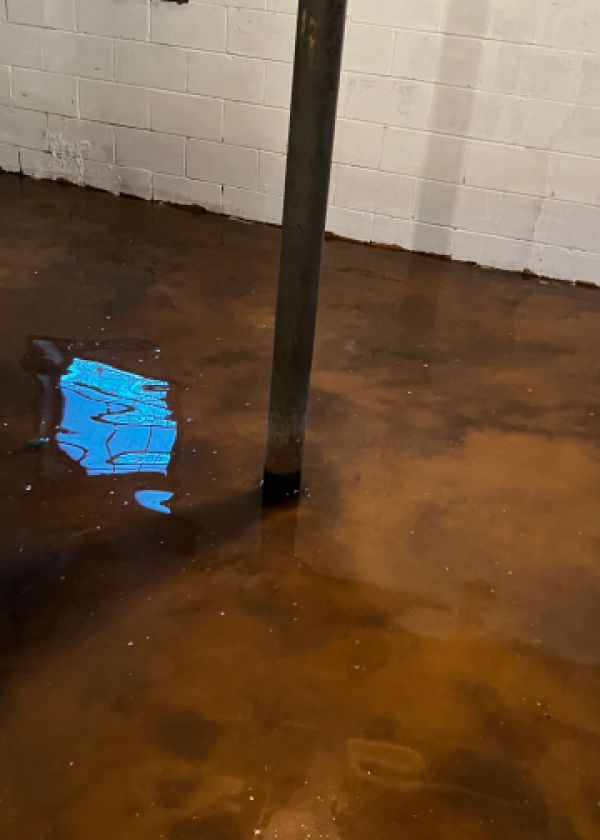 A flooded basement with a metal pole in the middle of it.