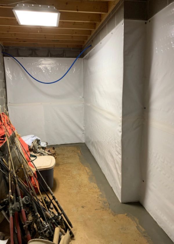 A room with a white tarp on the wall and a bunch of fishing rods.
