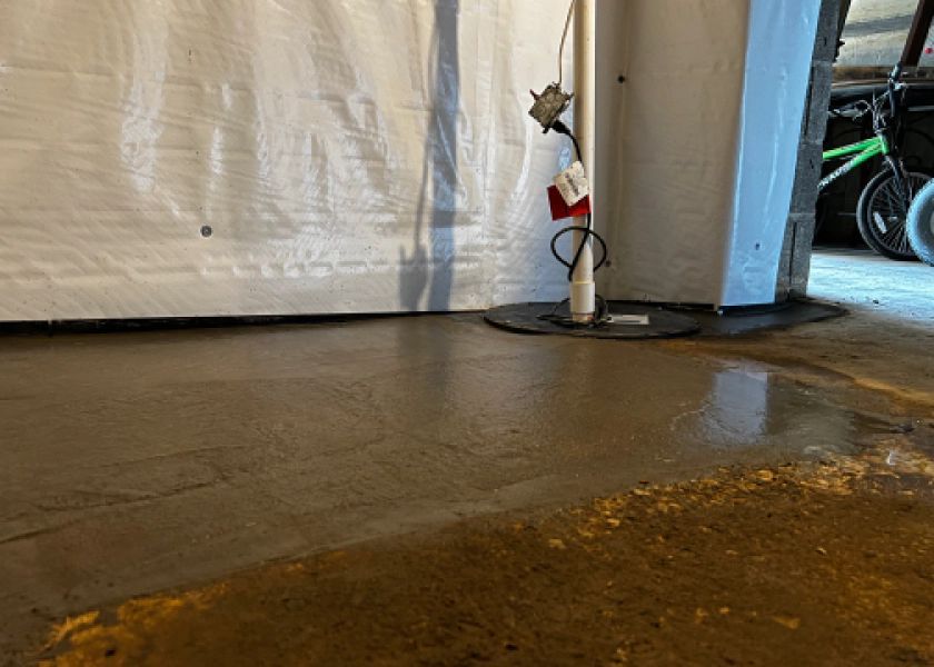 There is a puddle of water on the floor of a basement.