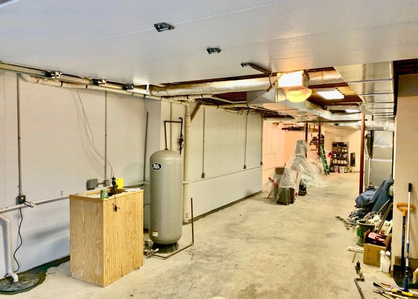 A large empty basement with a water tank and a wooden table.