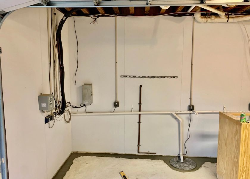 A basement with a lot of pipes and wires on the wall.
