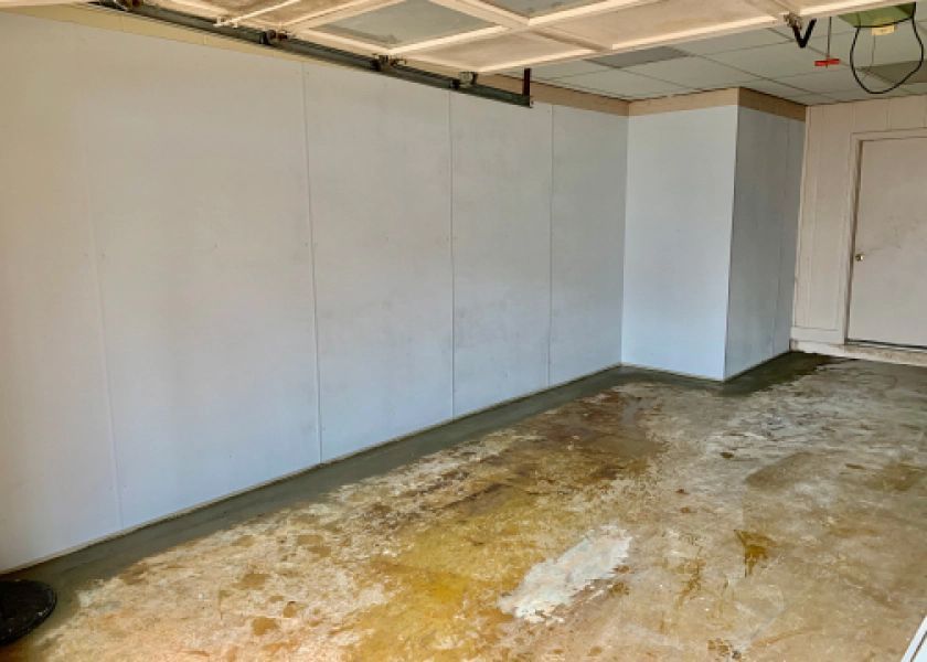 A garage with a concrete floor and a white wall.