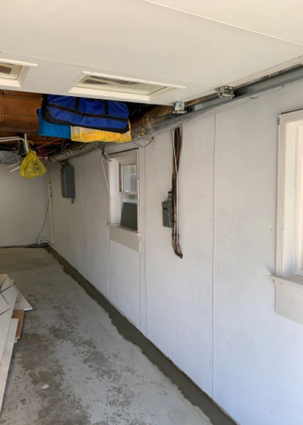 A long hallway in a garage with white walls and a window.