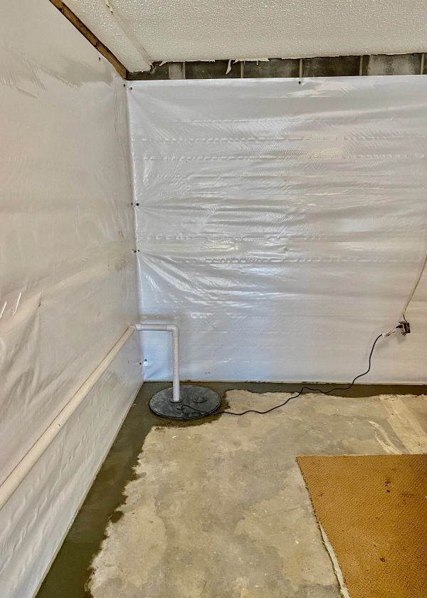 A room with a wall covered in plastic and a fan on the floor.