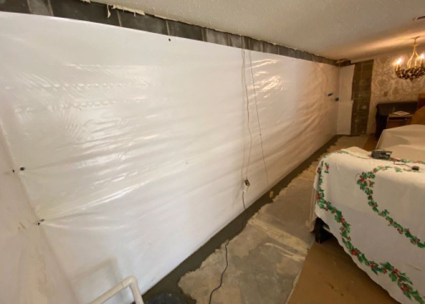 A bedroom with a bed and a wall covered in plastic.