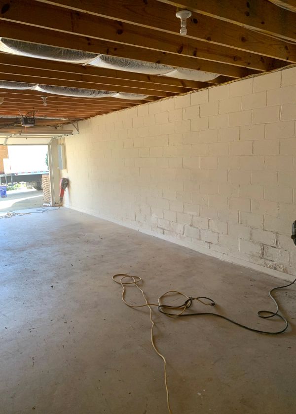 An empty garage with white brick walls and a wooden ceiling