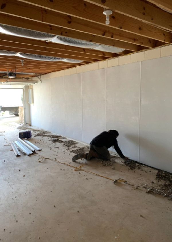 A man is working on a wall in a basement