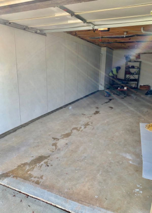 An empty garage with a white wall and a concrete floor.