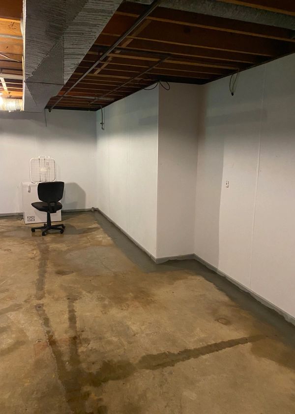 An empty basement with a chair and boxes on the floor.