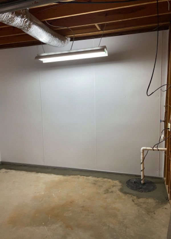 An empty basement with a light hanging from the ceiling.