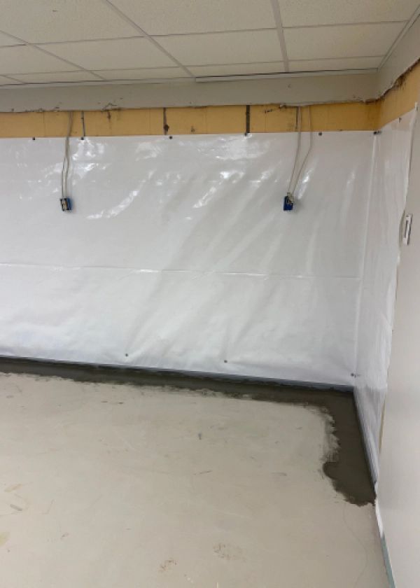 A room with a white wall and a concrete floor.