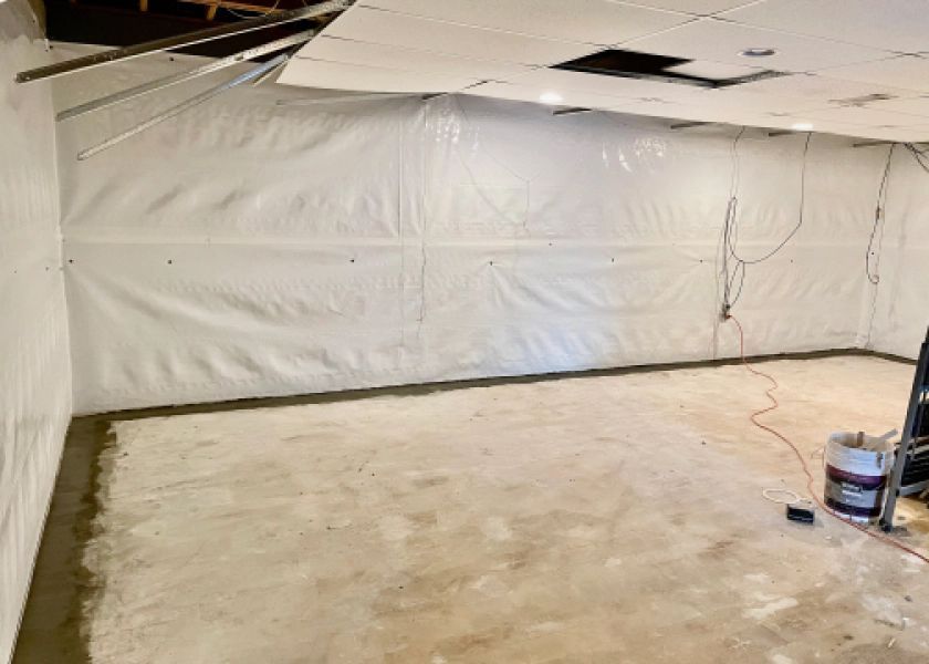 A basement with a hole in the ceiling and a vacuum cleaner on the floor.