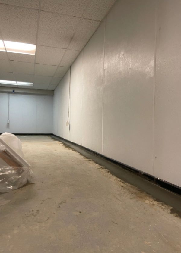 A long hallway with white walls and a concrete floor.