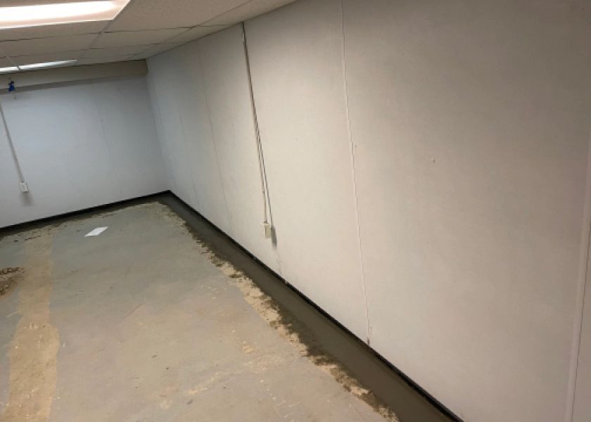 A room with a white wall and a concrete floor.