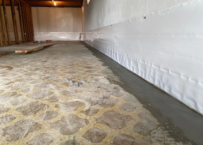A basement with a stone floor and a white wall.
