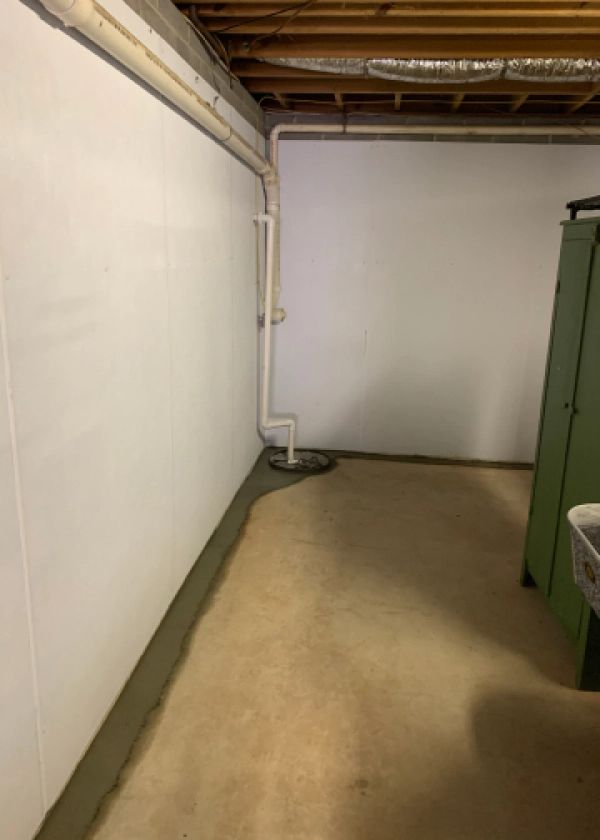 A basement with a white wall and a green cabinet.