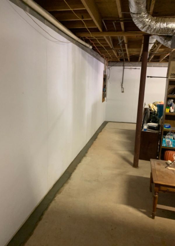 A long hallway in a basement with white walls and a wooden table.