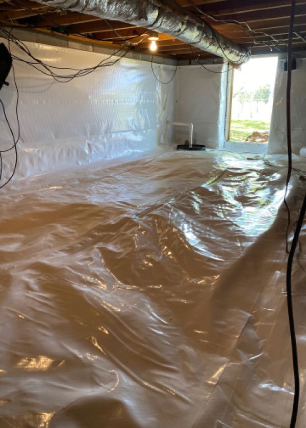 A basement with a lot of plastic covering the floor.